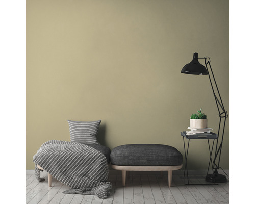 Dekorativní obytné prostředí s posezením, stojací lampou a pokojovou rostlinou na odkládacím stolku před jednobarevnou stěnou