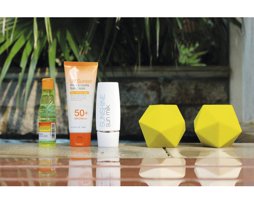 Opalovací krém, opalovací mléko a dva žluté dekorativní objekty