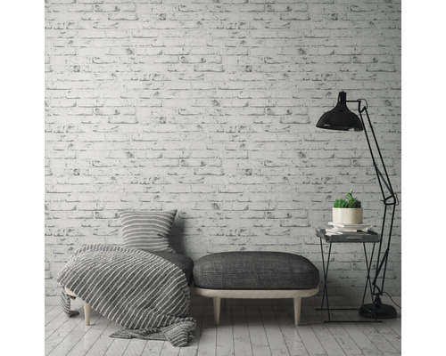 Dekorativní obývací pokoj s tapetou s cihlovým vzorem, posezením, stojací lampou a odkládacím stolkem.