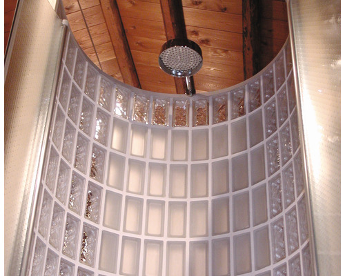 Zaoblený sprchový kout se skleněnými tvárnicemi a sprchovou hlavicí