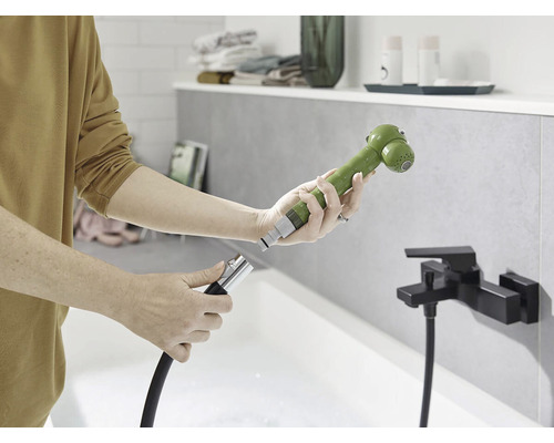 Osoba připojuje sprchovou hlavici k hadici v koupelně