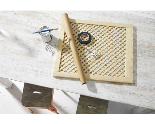 Dřevěný rám s mřížkou, plechovka barvy, štětec, role papíru, izolepa a nůžky na stole