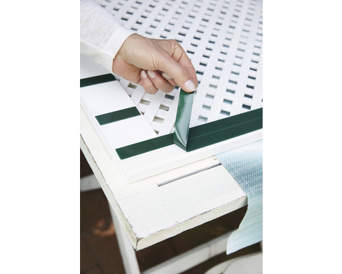 Osoba připevňuje samolepicí těsnicí pásku k plotovému prvku.