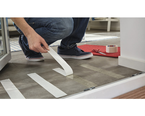 Osoba lepí lepicí pásku na podlahu