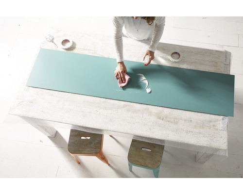 Žena čistí lakovanou desku čisticím prostředkem a hadříkem na stole.