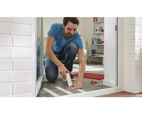 Muž lepí maskovací pásku na dlaždice pro malířské práce