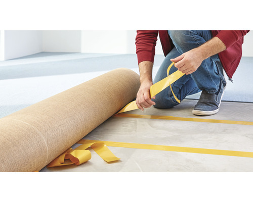 Osoba pokládá koberec pomocí oboustranné lepicí pásky