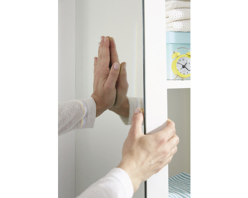 Osoba připevňuje zrcadlo ke skříni