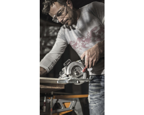 Muž řeže dřevěnou desku ruční okružní pilou Worx