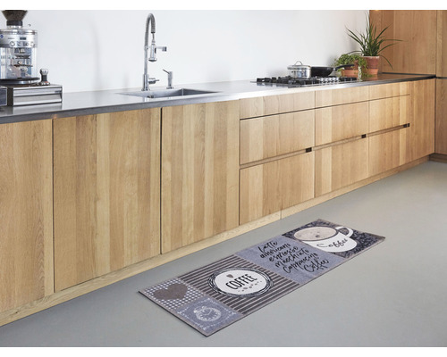 Kuchyně s dřevěnými skříňkami a kobercem s motivem kávy