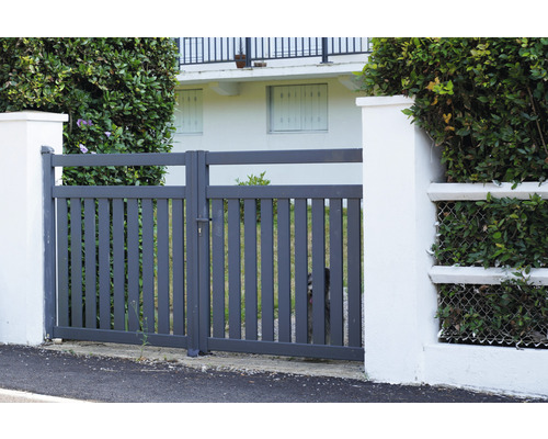 Šedá kovová zahradní branka mezi dvěma bílými pilíři