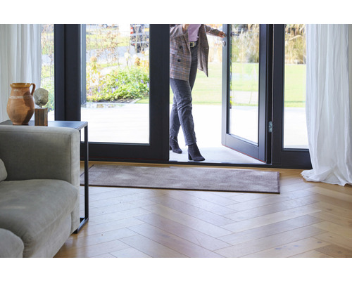 Vstupní prostor s rohožkou, dřevěnou podlahou a ženou procházející dveřmi