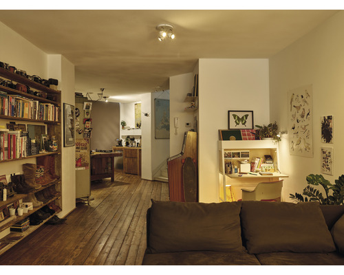 Interiér obývacího pokoje s dřevěnou podlahou, knihovnou a psacím stolem