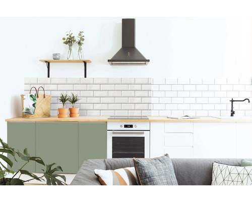 Moderní kuchyně s bílými obkladačkami metra, zelenými a bílými skříňkami, digestoří a dřevěnými prvky.