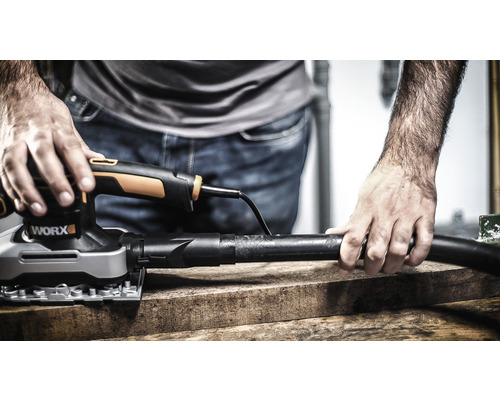 Muž brousí dřevěnou desku vibrační bruskou značky Worx