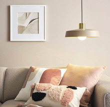 Obývací pokoj s visící lampou, polštáři a zarámovaným obrazem