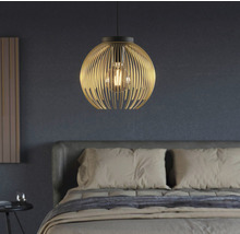 Závěsná lampa s kulovitým stínidlem z kovových tyčí nad postelí