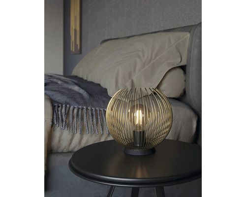 Dekorativní stolní lampa s kulovitým drátěným stínidlem na nočním stolku