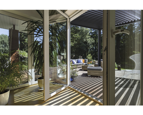 Pohled skleněnými dveřmi na terasu se zahradním nábytkem a pergolou