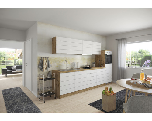 Moderní kuchyně s bílými skříňkami, dřevěnými detaily a jídelním stolem ve světlé místnosti.