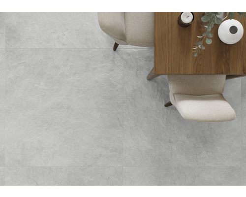 Světlá místnost s dlaždicemi se vzhledem kamene, stůl a židle.