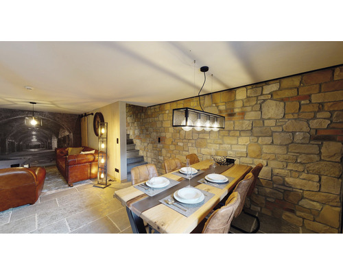 Obývací pokoj s jídelním stolem, židlemi, stojací lampou a kamennou zdí