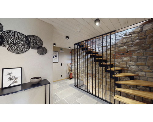 Interiérová fotografie chodby s kamenným schodištěm, nástěnnou dekorací a konzolou