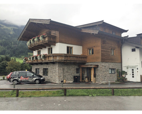 Vícepodlažní dům s dřevěnou fasádou a balkony s květinovou výzdobou