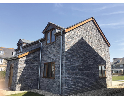 Exteriér domu s kamennými zdmi a sedlovou střechou