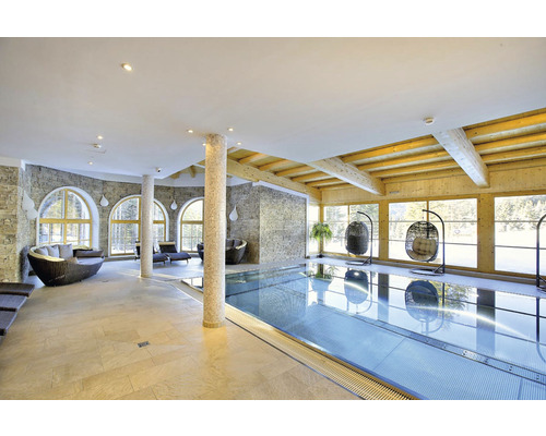 Světlý wellness prostor s bazénem, posezením a velkými okny pro dostatek denního světla