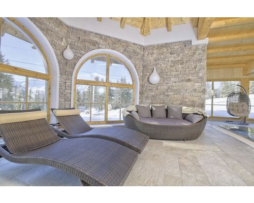 Relaxační místnost s lehátky, pohovkou a závěsným košem před velkými okny