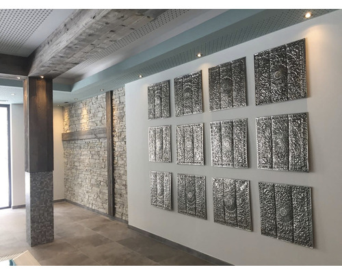 Interiér s dekorativními stěnovými panely, kamennými prvky a dřevěnými trámy.