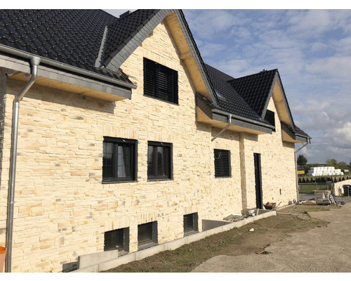 Dům s fasádou z přírodního kamene a tmavou taškovou střechou