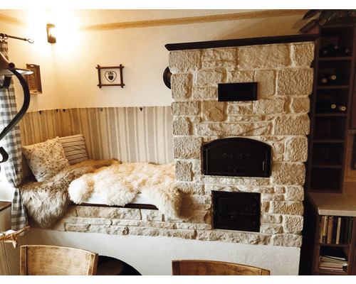 Pohodlné posezení s kachlovými kamny, polštáři a kožešinami ve světlé místnosti