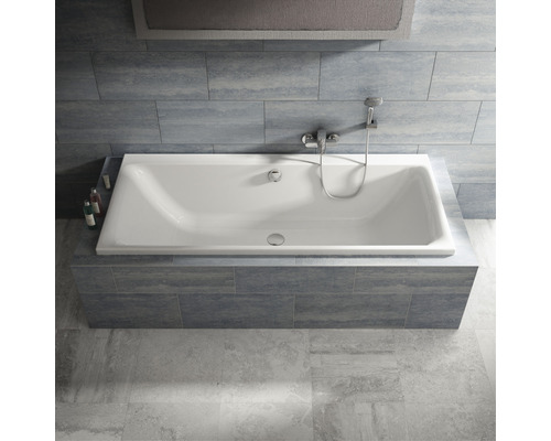 Obdélníková vana s armaturou a sprchovou hlavicí v koupelně s obklady