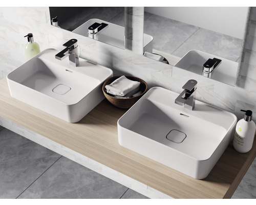 Koupelna se dvěma bílými umyvadly na desku, bateriemi a zrcadlem