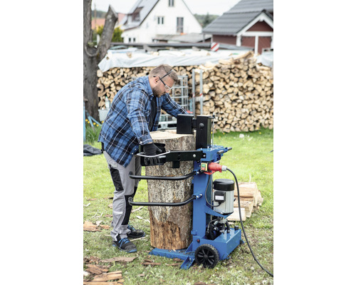 Muž štípe dříví s štípačkou venku