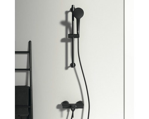 Sprchová souprava s tyčí a ruční sprchou před stěnou