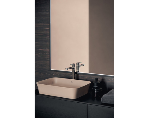 Béžové umyvadlo na desku na tmavé umyvadlové skříňce s vodovodní baterií a zrcadlem v koupelně