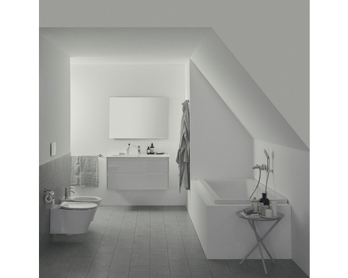 Světlá koupelna s vanou, umyvadlem a toaletou v podkroví.