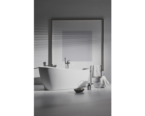 Volně stojící vana s baterií, držákem na ručníky a koupelnovými doplňky v koupelně.