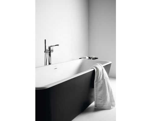 Volně stojící vana s baterií a ručníkem v koupelně.