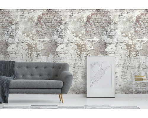 Obývací pokoj se šedou pohovkou před tapetou imituje odlupující se cihlovou zeď.