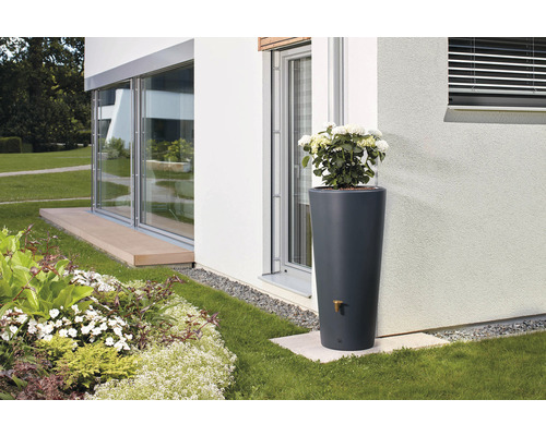 Nádrž na dešťovou vodu ve tvaru sloupu s miskou na rostliny a vodovodním kohoutkem na zahradě