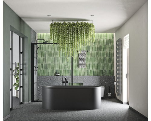 Moderní koupelna s černou vanou, zelenými obklady a závěsnými rostlinami pro světlou a uspořádanou atmosféru.