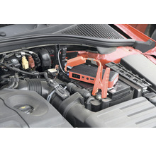 Startovací booster připojený k autobaterii v motorovém prostoru