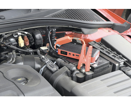 Startovací booster připojený k autobaterii v motorovém prostoru