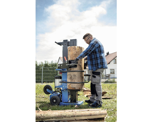 Muž obsluhuje štípačku dřeva venku.