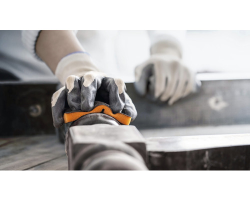 Osoba s rukavicemi brousí obrobek brusným blokem