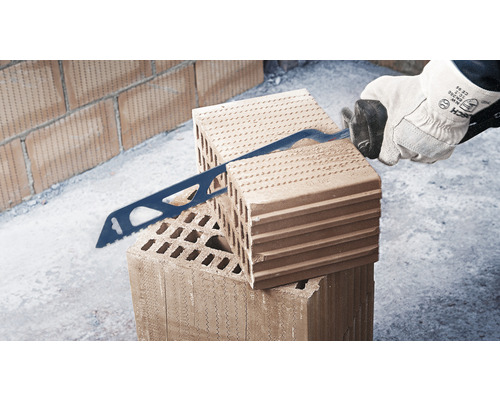 Muž řeže cihlu pilou.